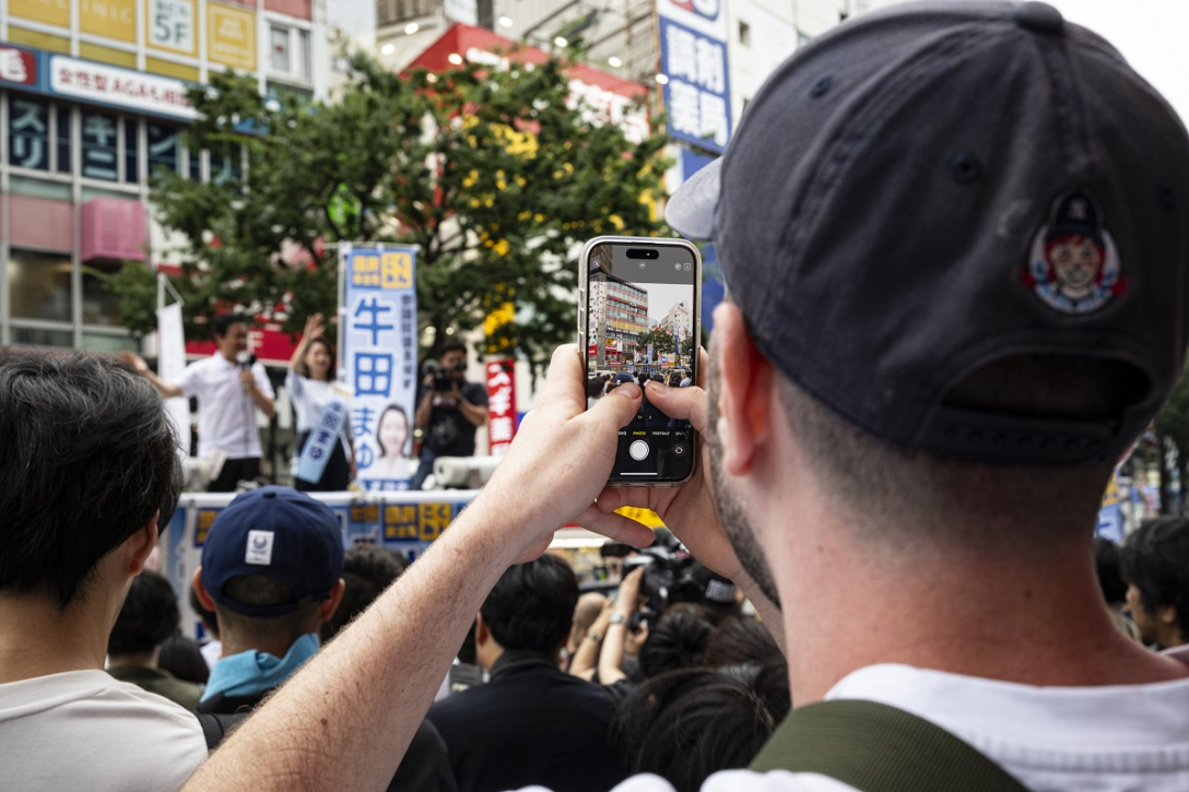 Мужчина снимает на смартфон акцию