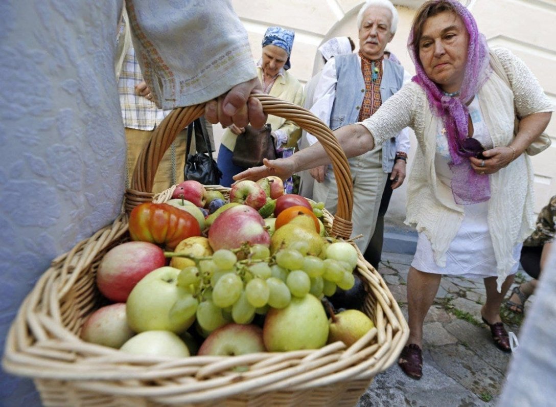 Яблучний Спас — жінка святить яблука і виноград, фрукти в кошику