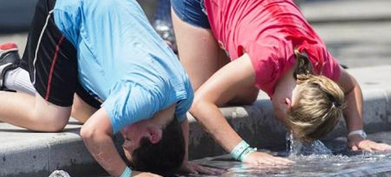 Дети опускают головы в фонтан