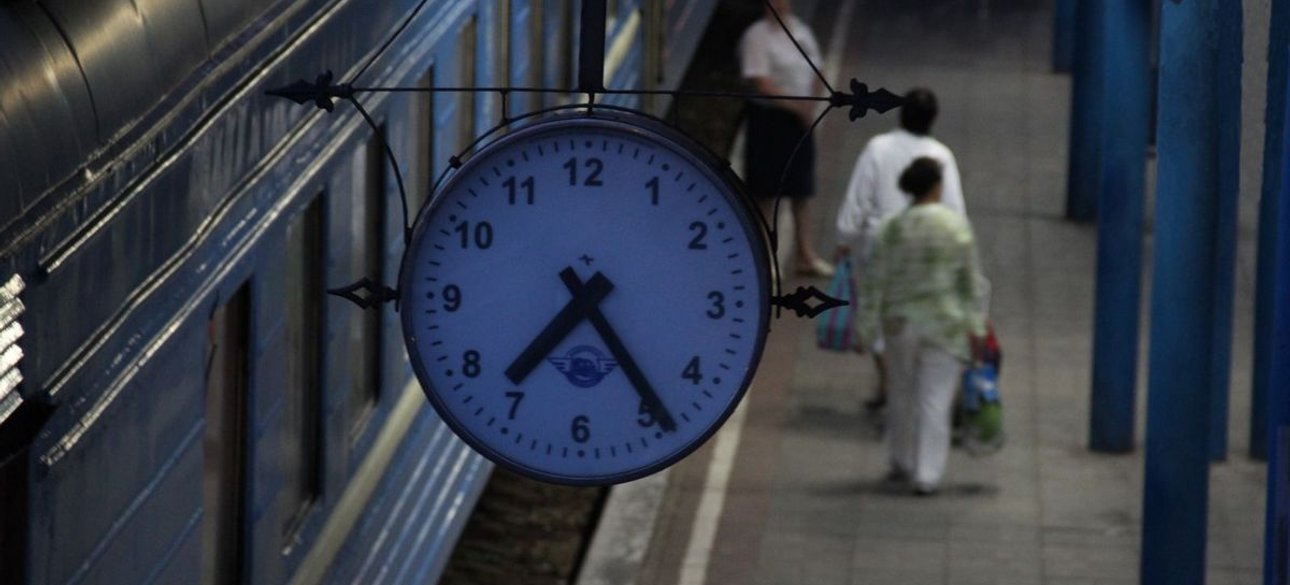 Пассажиры и часы на перроне железнодорожного вокзала