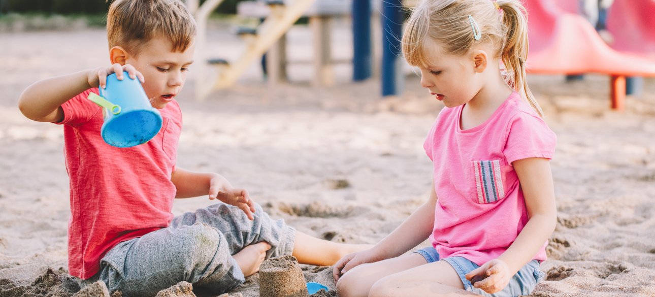 Мальчик и девочка играют в песочнице