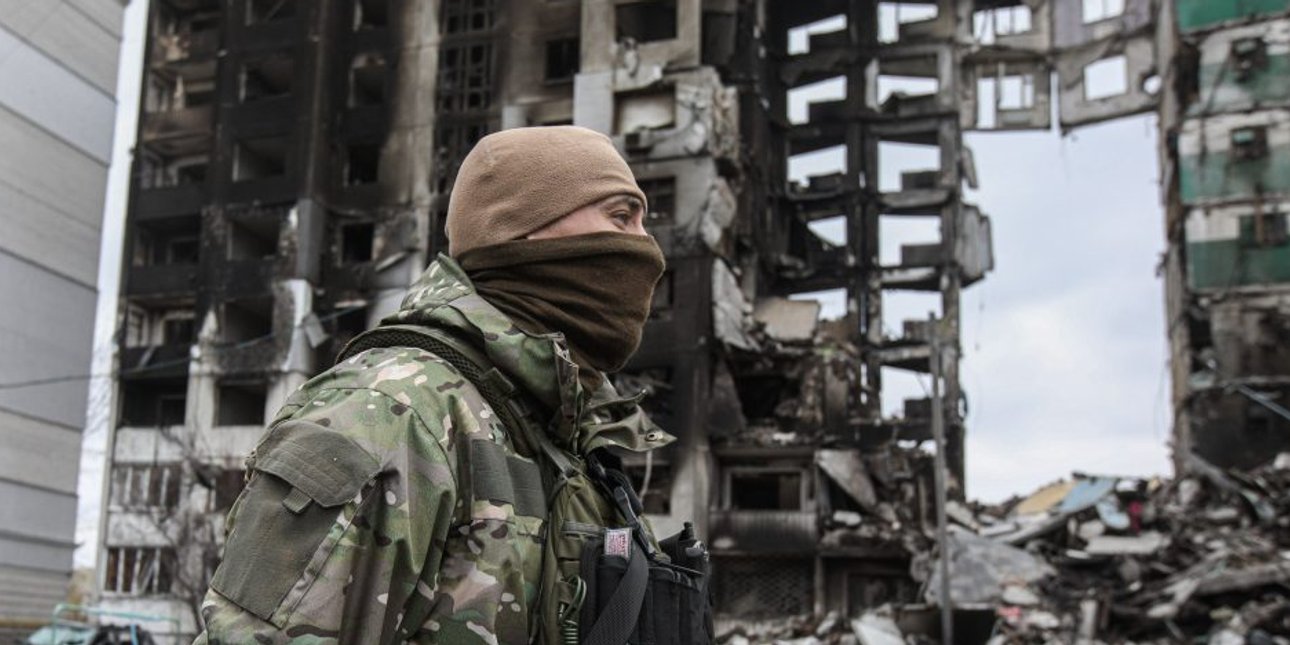 Украинский военнослужащий на фоне разрушенного здания