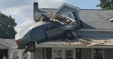 Залишився висіти на даху: автомобіль злетів у повітря та врізався в житловий будинок (фото)