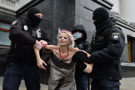 полицейские держат активистку Femen
