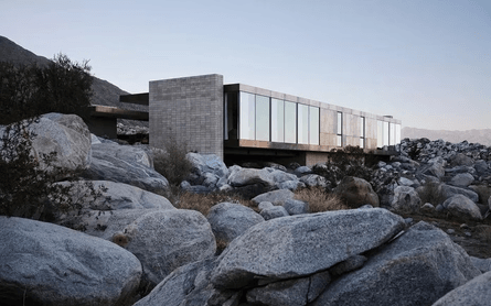 Современная вилла посреди пустыни с мостом и бассейном в скалах