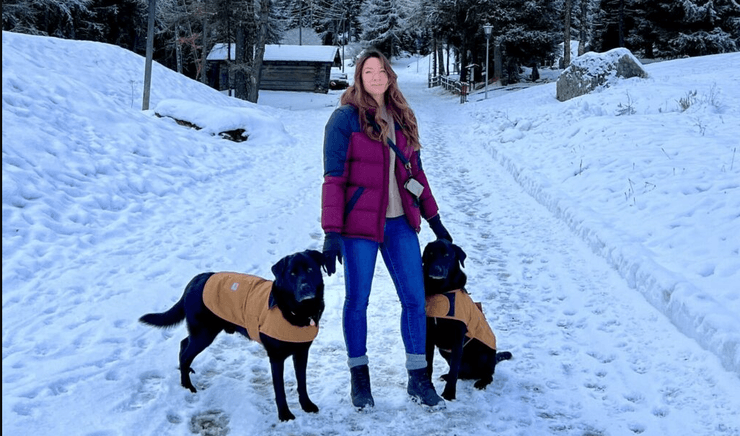 Женщина с двумя собаками в зимнем лесу во время путешествия по Европе