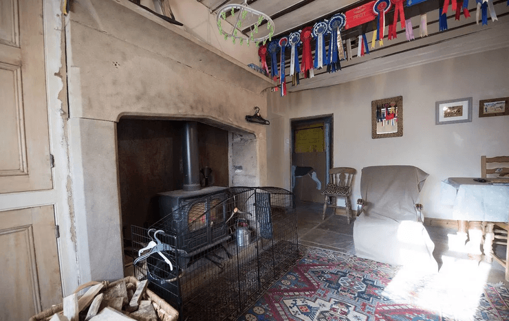 Вітальня всередині ферми Стотт-Голл з каміном, старовинними стінами і нагородами, що висять під стелею