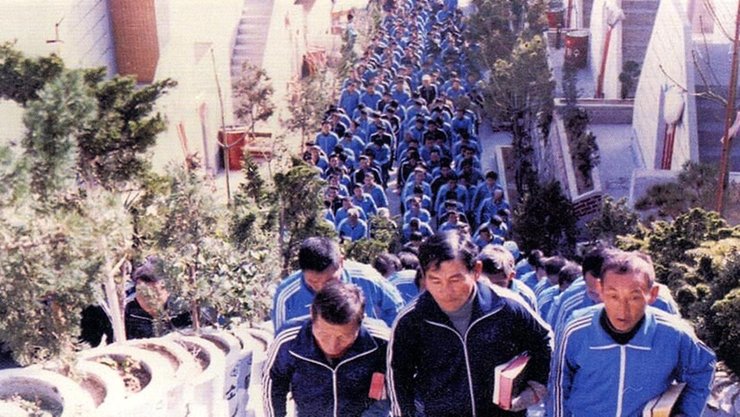 В'язні табору у синіх спортивних костюмах