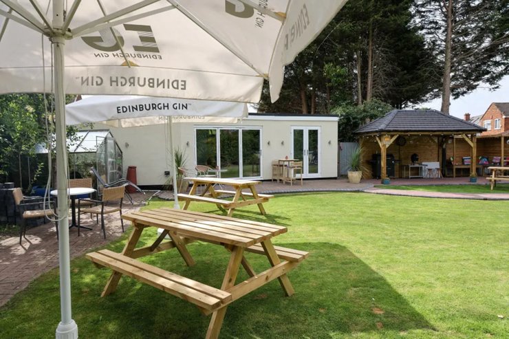 Вид на сад із зонами відпочинку та паб Cognitos на задньому дворі будинку