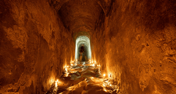 Історичний підземний тунель Микільської дренажної системи в Києві, освітлений свічками і частково заповнений водою