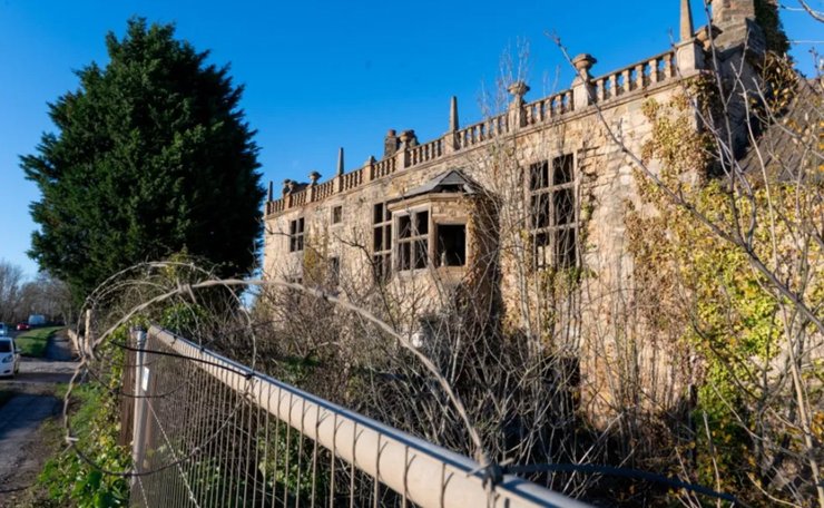 Зруйнований фасад старовинного особняка з порожніми віконними прорізами і слідами