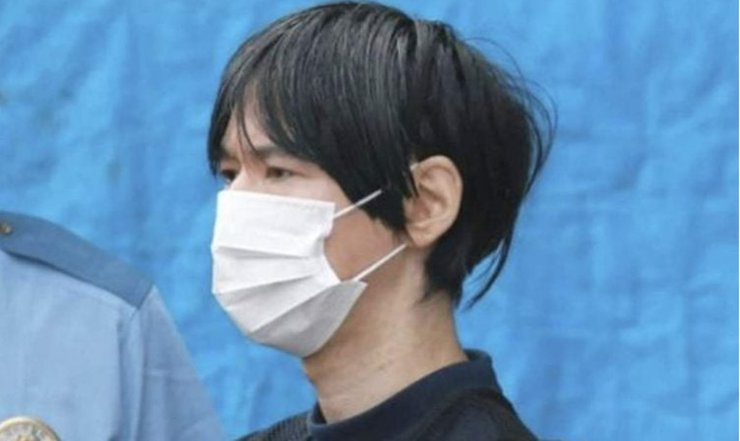 Мужчина в защитной маске под конвоем полиции в Японии после обвинения в мошенничестве