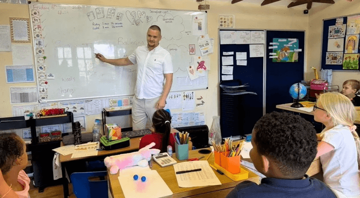 Чоловік веде урок перед дітьми в компактній домашній школі, побудованій на задньому дворі