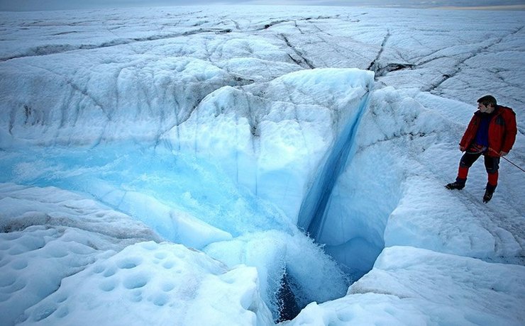 Поверхнева тала вода тече в отвори до нижньої частини льодовикового покриву Гренландії.