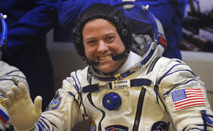 Астронавт в скафандре улыбается перед стартом миссии на Международную космическую станцию