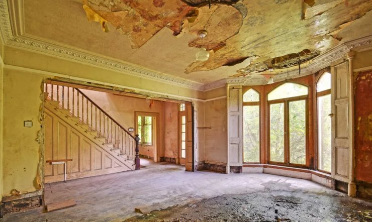 Зруйнований інтер'єр котеджу XIX століття з облупленою стелею і пошкодженими стінами