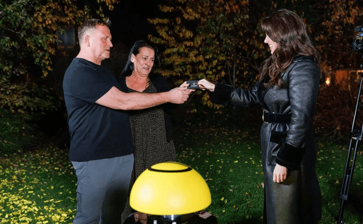 Представитель Omaze вручает Кристиану и Лесли Джонс карту с подтверждением их миллионного выигрыша