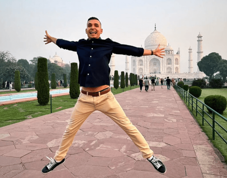 Мужчина в прыжке позирует на аллее перед Тадж-Махалом в Индии