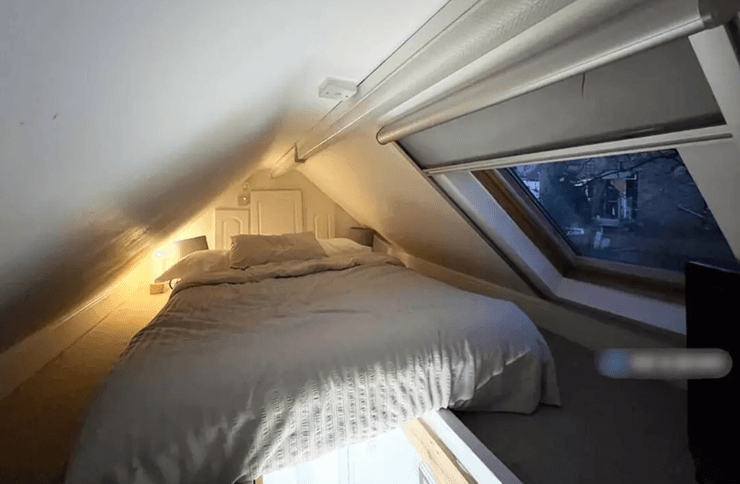 Кровать на чердаке с низким потолком и окном в лондонской квартире