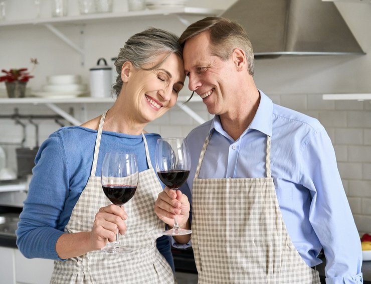 Пара в кухонных передниках, бокалы вина - фото