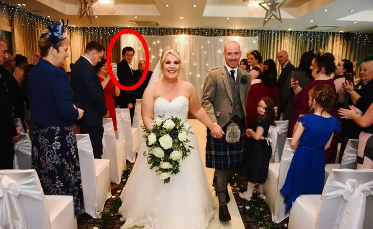 Случайный гость стоит в проходе позади невесты и жениха во время церемонии в отеле Carlton, Прествик