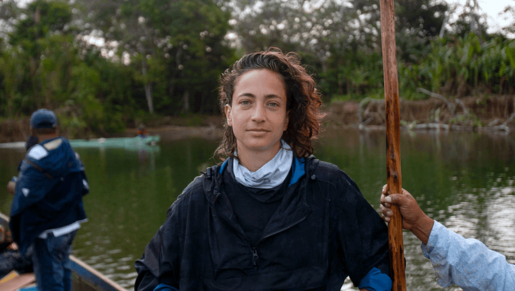 Паола Рамос стоїть у човні на річці в Дар'єнському пробілі, оточена джунглями, під час репортажу про мігрантів