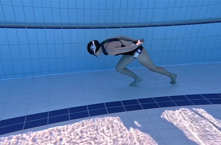 Во время подводного плавания женщина сгибает спину под углом 90 градусов и таком положении передвигается по дну бассейна