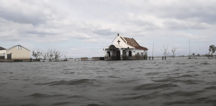 Белая церковь с красной крышей, частично затопленная морем на филиппинском острове