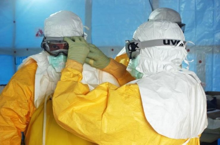 Медицинские работники надевают защитную одежду перед входом в отделение лечения Эболы в Либерии.