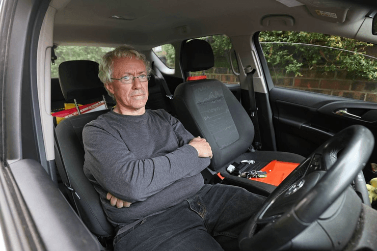 Майкл Аткинсон сидит в салоне Vauxhall Meriva, где он живет уже несколько месяцев