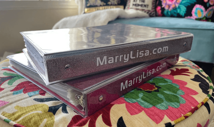 Две папки с надпис MarryLisa.com, поставени върху цветна възглавница