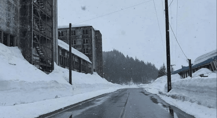 Заснеженная дорога в Уиттиере на Аляске зимой, окружающие заброшенные здания и глубокие сугробы