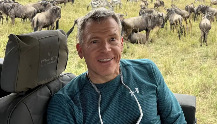 Мужчина сидит в открытом джипе во время сафари на фоне саванны и заката