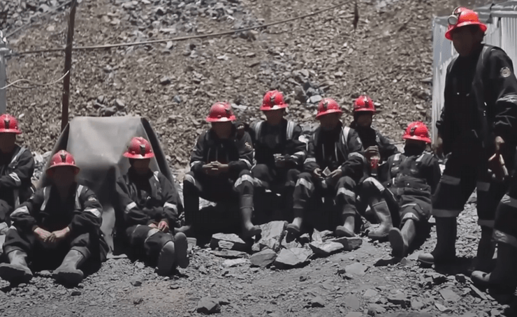 Группа шахтеров в красных касках сидит у шахты в Ла-Ринконаде, Перу