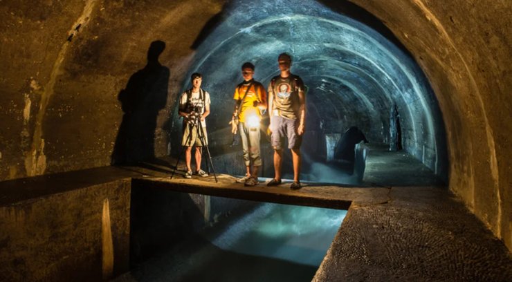 Група дослідників стоїть усередині колектора Полтви над бурхливим підземним потоком