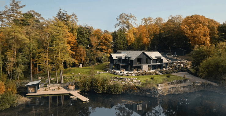 Современный особняк на берегу частного озера с причалом, окруженный осенним лесом
