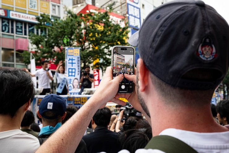 Мужчина снимает на смартфон акцию