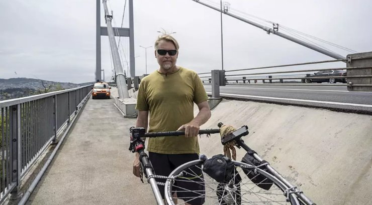 Британский путешественник Карл Бушби стоит на мосту с походной тележкой во время своего 27-летнего пешего маршрута