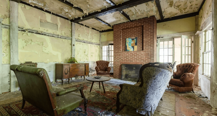 Гостиная заброшенного дома с камином, старинными креслами и облупившимися стенами