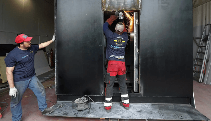 Рабочие собирают металлический модуль частного убежища в цеху