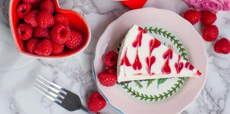 Малиновий чізкейк на тарілці з серцевим візерунком і ягодами малини