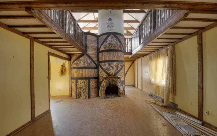 Інтер'єр покинутого особняка в стилі Тюдорів з унікальним цегляним каміном і гвинтовими сходами, що ведуть на балкон