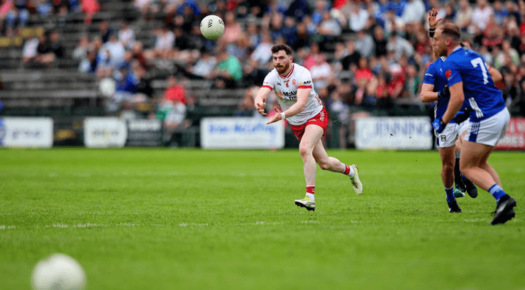 Гравець робить передачу м'яча рукою під час матчу з гельського футболу, показуючи, як різні дисципліни дозволяють те, що заборонено в класичному футболі