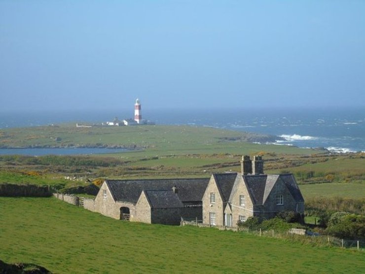 Каменный фермерский дом и зеленые поля на удаленном острове Инис-Энлли, где открыта вакансия для ухода за овцами