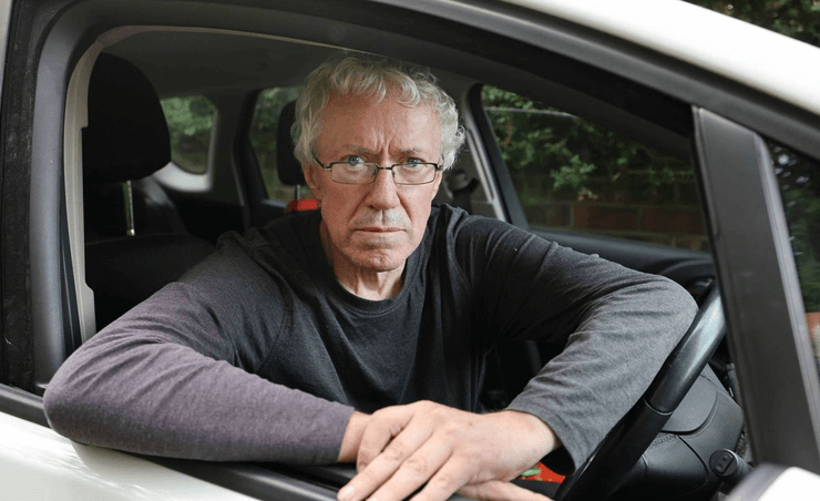 Мужчина сидит за рулем своей машины, где ему приходится жить и работать после развода