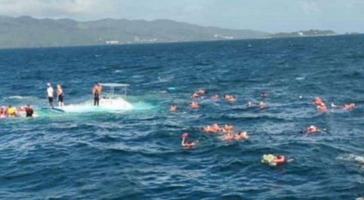 Люди в спасательных жилетах плывут к берегу после того, как экскурсионный катамаран затонул недалеко от залива Самана