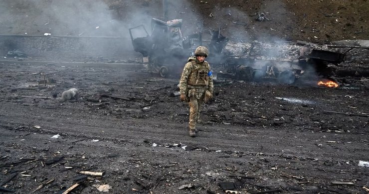 украинский солдат и сожженная техника врага