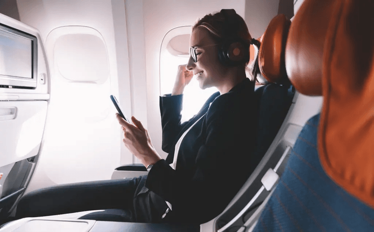 Женщина в самолете пользуется смартфоном в самолете