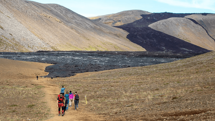 Туристы идут по тропе к лавовому полю Фаградальсфьядль, Исландия