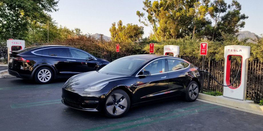 Электрокар Tesla Model 3 стоит на стоянке и заряжается